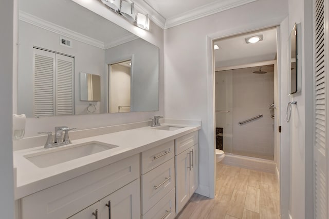 bathroom featuring toilet, crown molding, a shower with shower door, dual sinks, and oversized vanity