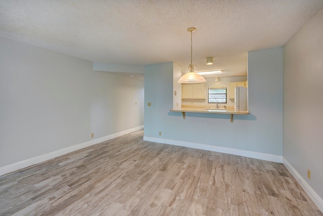 unfurnished living room with light hardwood / wood-style floors, a textured ceiling, and sink