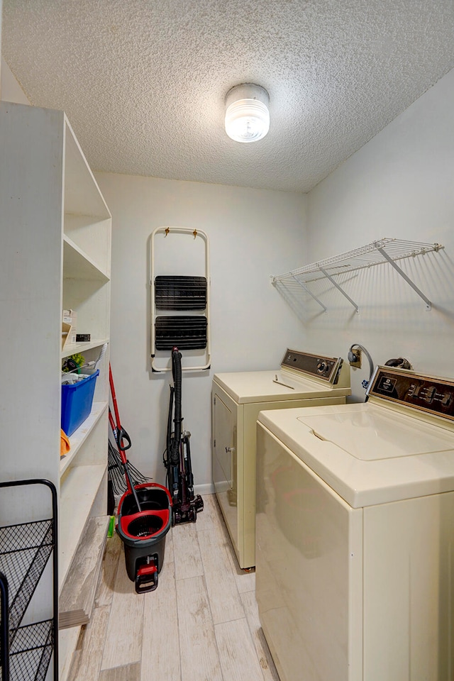 laundry area featuring washer and dryer, light hardwood / wood-style floors, and a textured ceiling