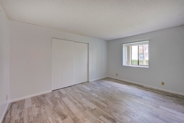 unfurnished bedroom featuring light hardwood / wood-style floors, a textured ceiling, and a closet