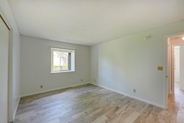 unfurnished room featuring light hardwood / wood-style flooring and a textured ceiling