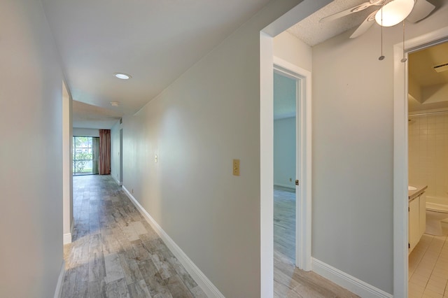 hallway with light hardwood / wood-style floors and a textured ceiling