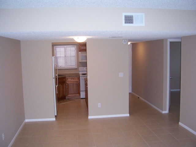 tiled spare room with a textured ceiling