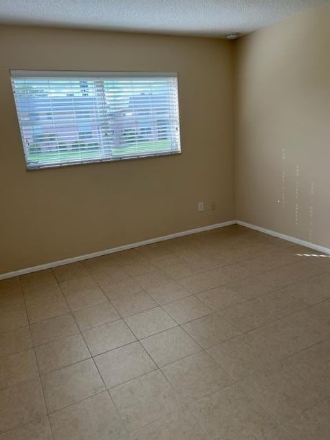 spare room with a textured ceiling and light tile flooring