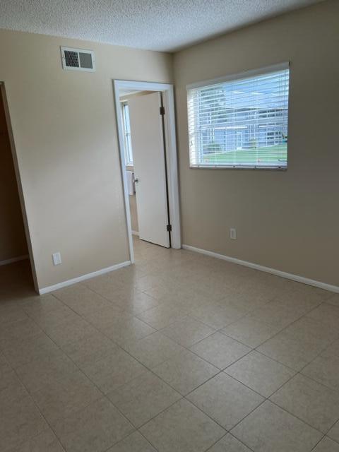 tiled empty room with a textured ceiling