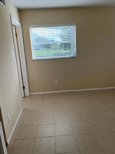 tiled spare room with a textured ceiling and a wealth of natural light