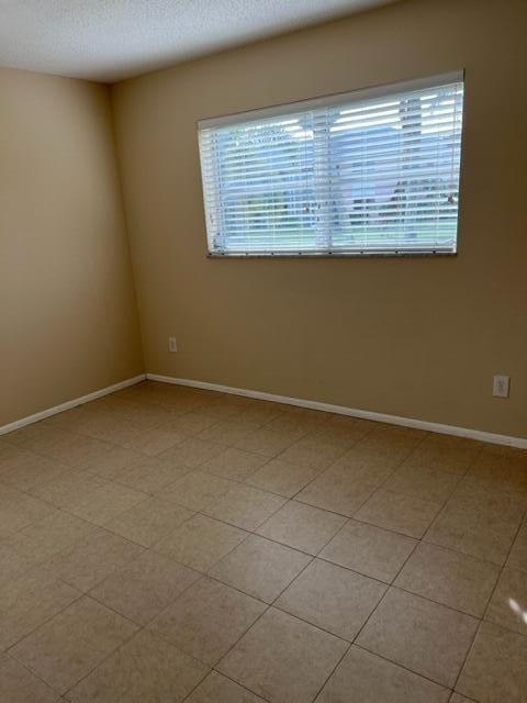 tiled empty room with a textured ceiling