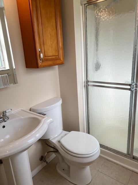 bathroom with an enclosed shower, toilet, sink, and tile flooring