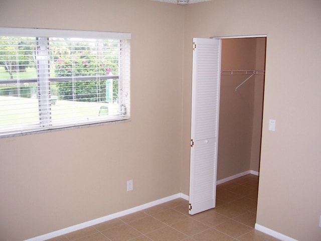 unfurnished bedroom with a closet and light tile floors