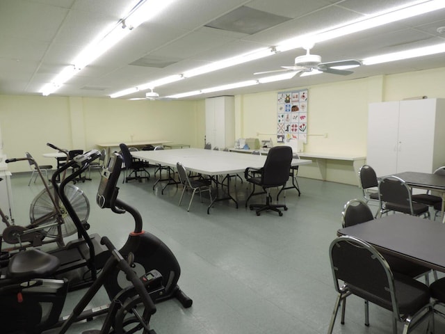 workout area featuring a paneled ceiling, ceiling fan, and light tile floors