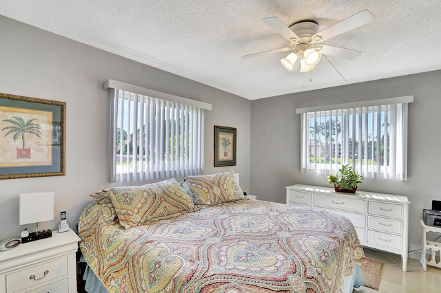 tiled bedroom with ceiling fan and a textured ceiling