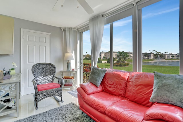 sunroom featuring ceiling fan and a water view