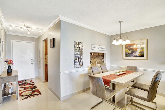 tiled dining area with crown molding, rail lighting, a chandelier, and a textured ceiling