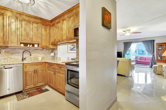 kitchen with appliances with stainless steel finishes, light stone counters, light tile floors, ceiling fan, and sink