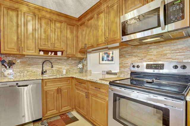 kitchen featuring backsplash, sink, light stone counters, and stainless steel appliances