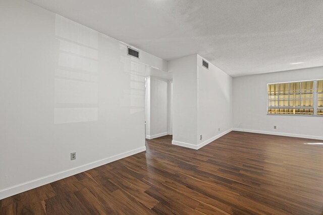 spare room featuring a textured ceiling and dark hardwood / wood-style flooring