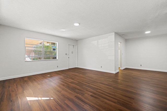 unfurnished room with a textured ceiling and dark hardwood / wood-style flooring