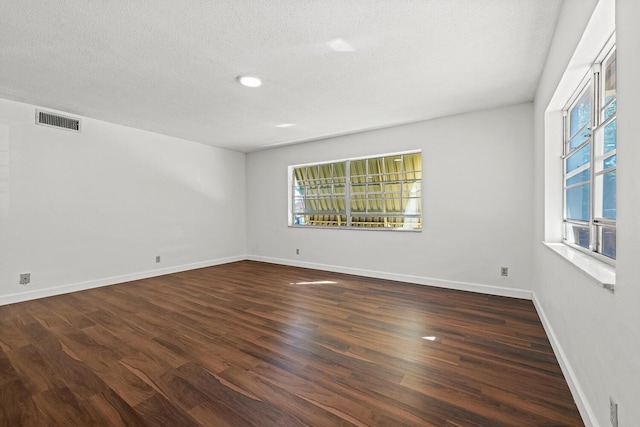 empty room with dark wood-type flooring and a textured ceiling