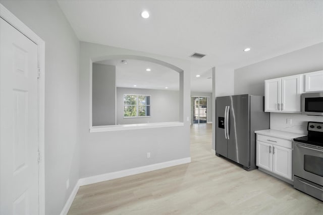 kitchen featuring white cabinets, light hardwood / wood-style flooring, light stone countertops, and stainless steel appliances