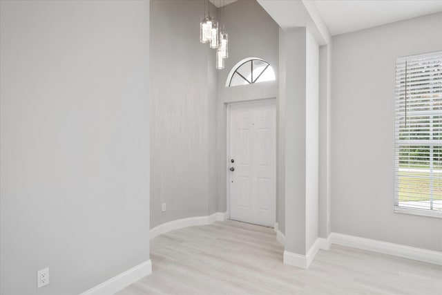 foyer entrance with light wood-type flooring and an inviting chandelier