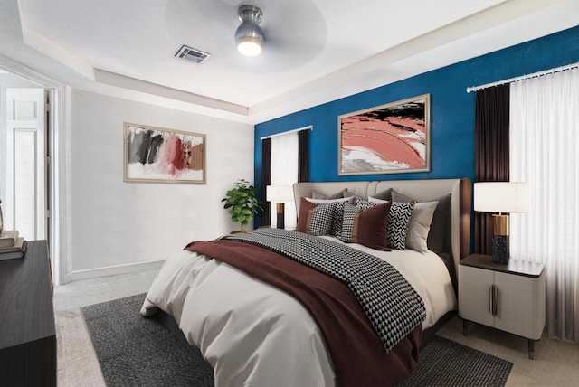 bedroom featuring dark carpet, a raised ceiling, and ceiling fan