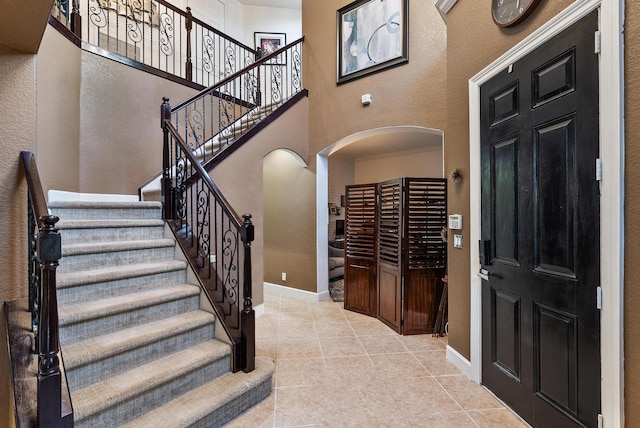 foyer entrance featuring light tile floors and crown molding