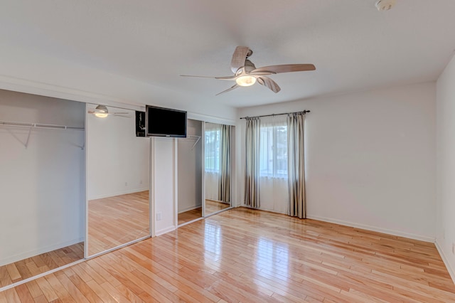 unfurnished bedroom featuring two closets, ceiling fan, and light hardwood / wood-style flooring