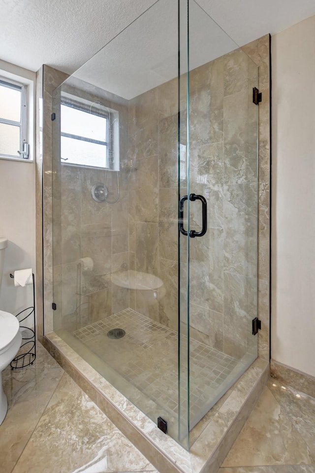 bathroom with tile floors, a shower with shower door, and a healthy amount of sunlight