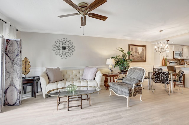 living room featuring crown molding, light wood-type flooring, and ceiling fan with notable chandelier