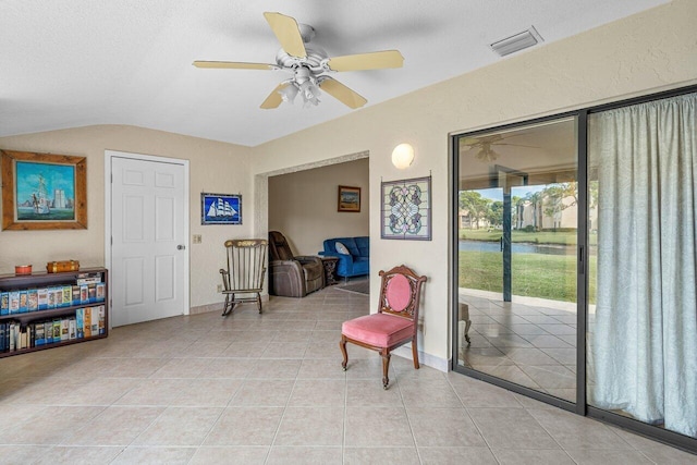 sitting room with ceiling fan, light tile floors, and lofted ceiling