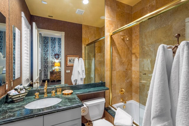 full bathroom featuring combined bath / shower with glass door, toilet, and large vanity