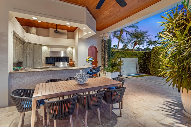 patio terrace at dusk featuring a bar and ceiling fan