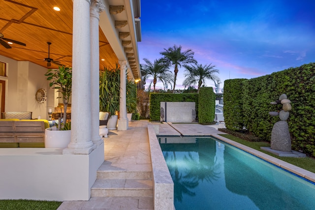 pool at dusk with a patio area and ceiling fan