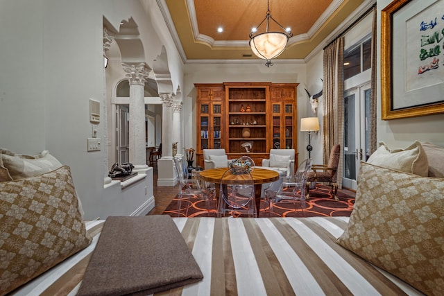 interior space with a high ceiling, crown molding, a tray ceiling, decorative columns, and dark hardwood / wood-style floors