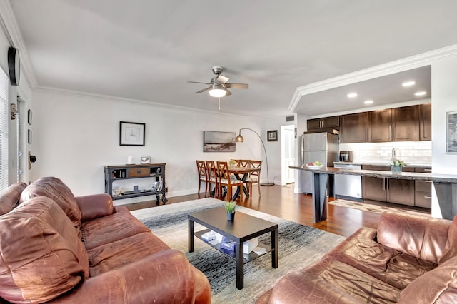 living room featuring crown molding, light hardwood / wood-style flooring, and ceiling fan