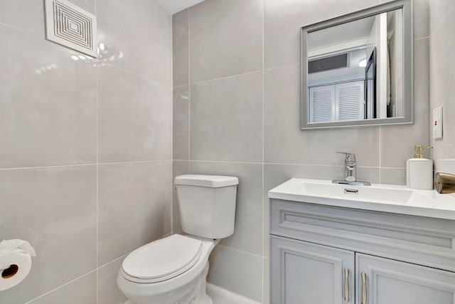 bathroom with vanity, tile walls, and toilet