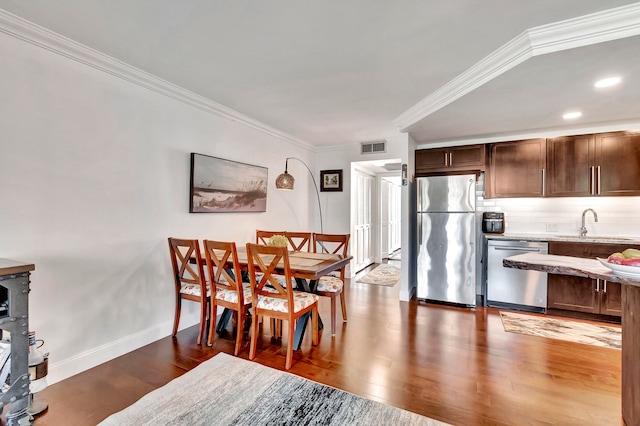 dining area featuring crown molding, dark wood-type flooring, and sink