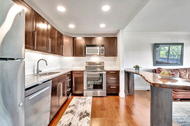 kitchen featuring crown molding, sink, stainless steel appliances, and light hardwood / wood-style floors