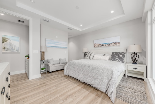 bedroom with a raised ceiling and light wood-type flooring