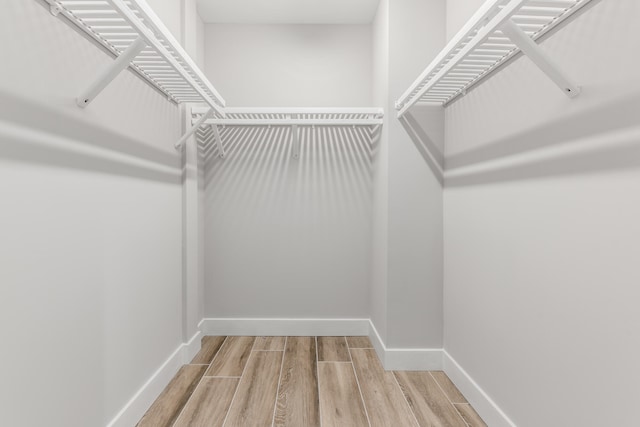 walk in closet with light hardwood / wood-style flooring