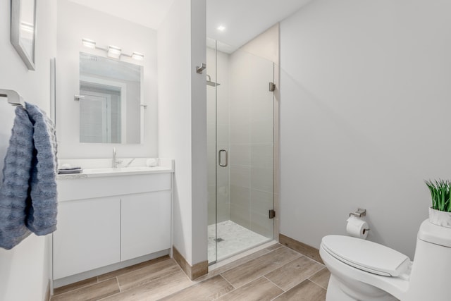 bathroom featuring oversized vanity, toilet, and a shower with door