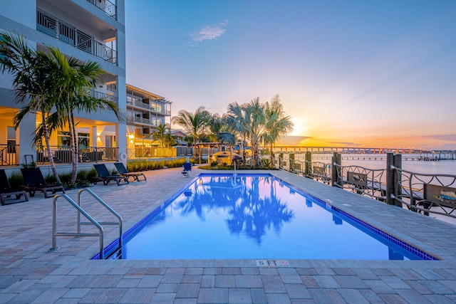 pool at dusk featuring a patio