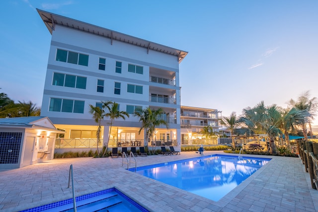 pool at dusk with a patio area