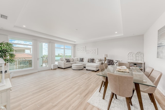 dining space with a raised ceiling and light hardwood / wood-style floors