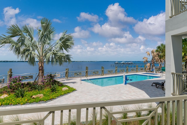 view of pool with a water view and a patio