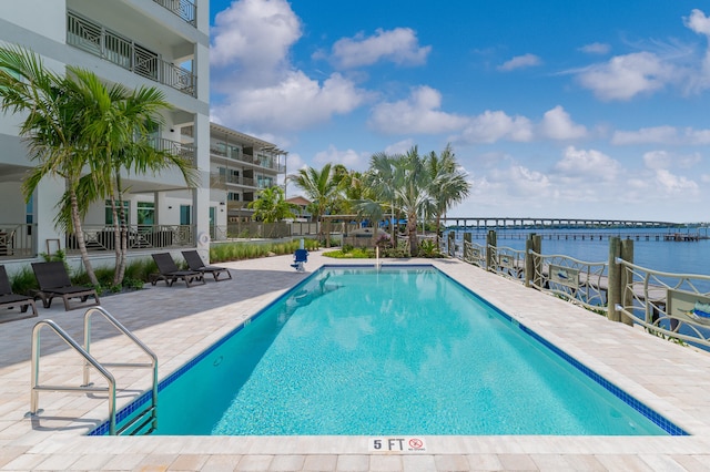 view of pool with a water view and a patio