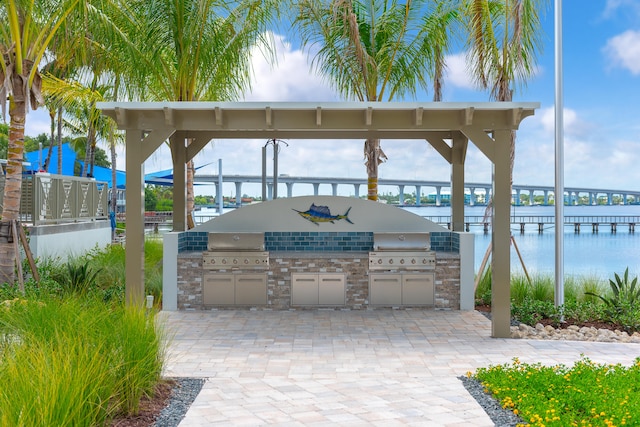 view of patio / terrace with area for grilling, a water view, and exterior kitchen