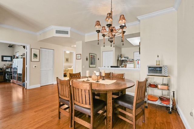 dining space featuring crown molding, hardwood / wood-style flooring, and an inviting chandelier