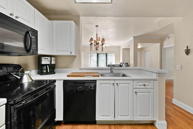 kitchen with sink, white cabinets, black appliances, a notable chandelier, and light wood-type flooring