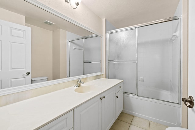 full bathroom featuring tile floors, a textured ceiling, toilet, oversized vanity, and enclosed tub / shower combo